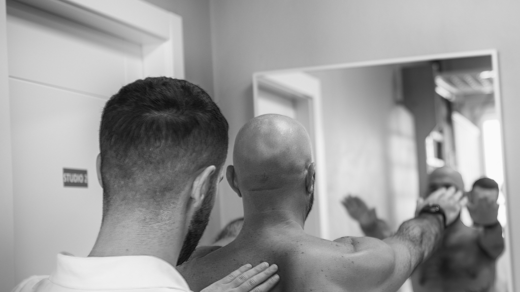 Un kinésithérapeute évalue l’épaule d’un patient en testant la mobilité et la force des muscles de la coiffe des rotateurs, première étape essentielle du traitement d’une tendinite d’épaule.